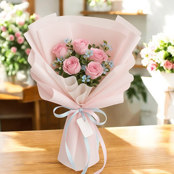ช่อดอกไม้ Sweet Sky Bouquet – ช่อดอกไม้กุหลาบชมพู แซมดอกอ๊อกซี่สีฟ้า ห่อกระดาษชมพู ผูกโบว์ฟ้าชมพู